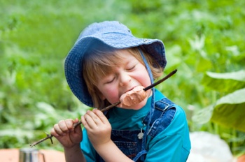 kid eating sausage from stick