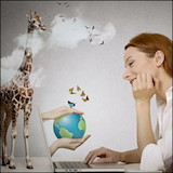 Woman dreaming of vacation at laptop with giraffe in background