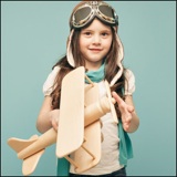 little girl holding wooden toy airplane