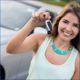 Happy young woman with keys to rental car