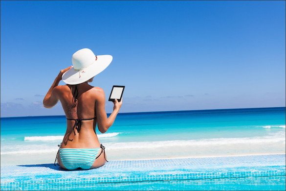 woman at edge of pool wearing a bikini and reading a kindle