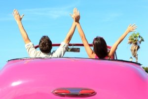 couple with hands in the air in pink convertable